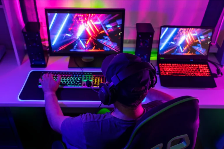 Gamer comparing a custom vs pre-built gaming PC setup with RGB keyboard and dual monitors